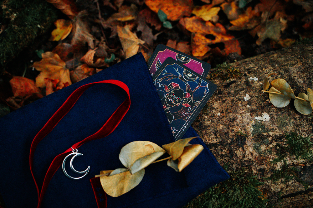 Pochette bleue avec ruban rouge d'où sort des cartes de tarot